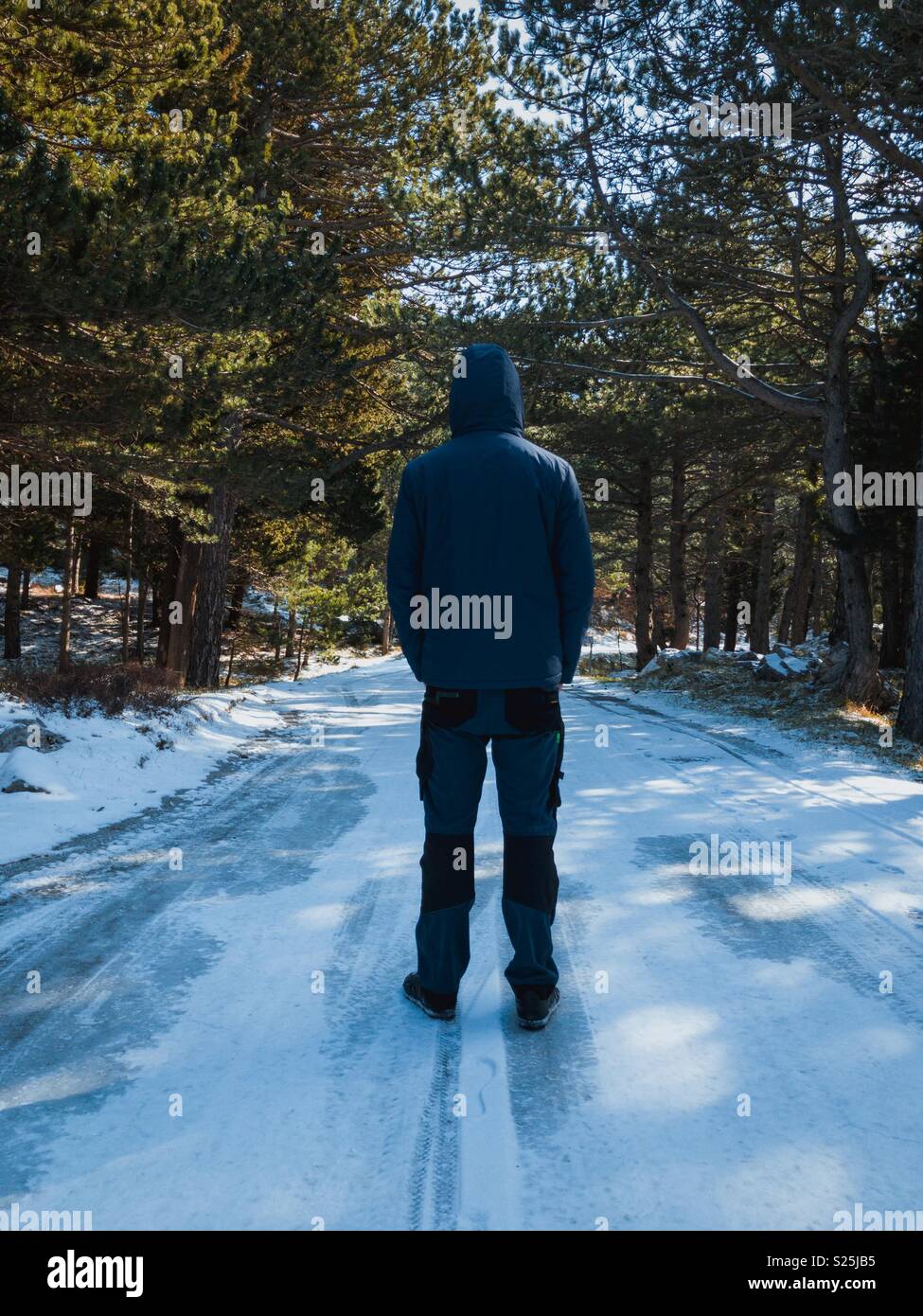 Man walking on frozen mountain road in nature park Stock Photo