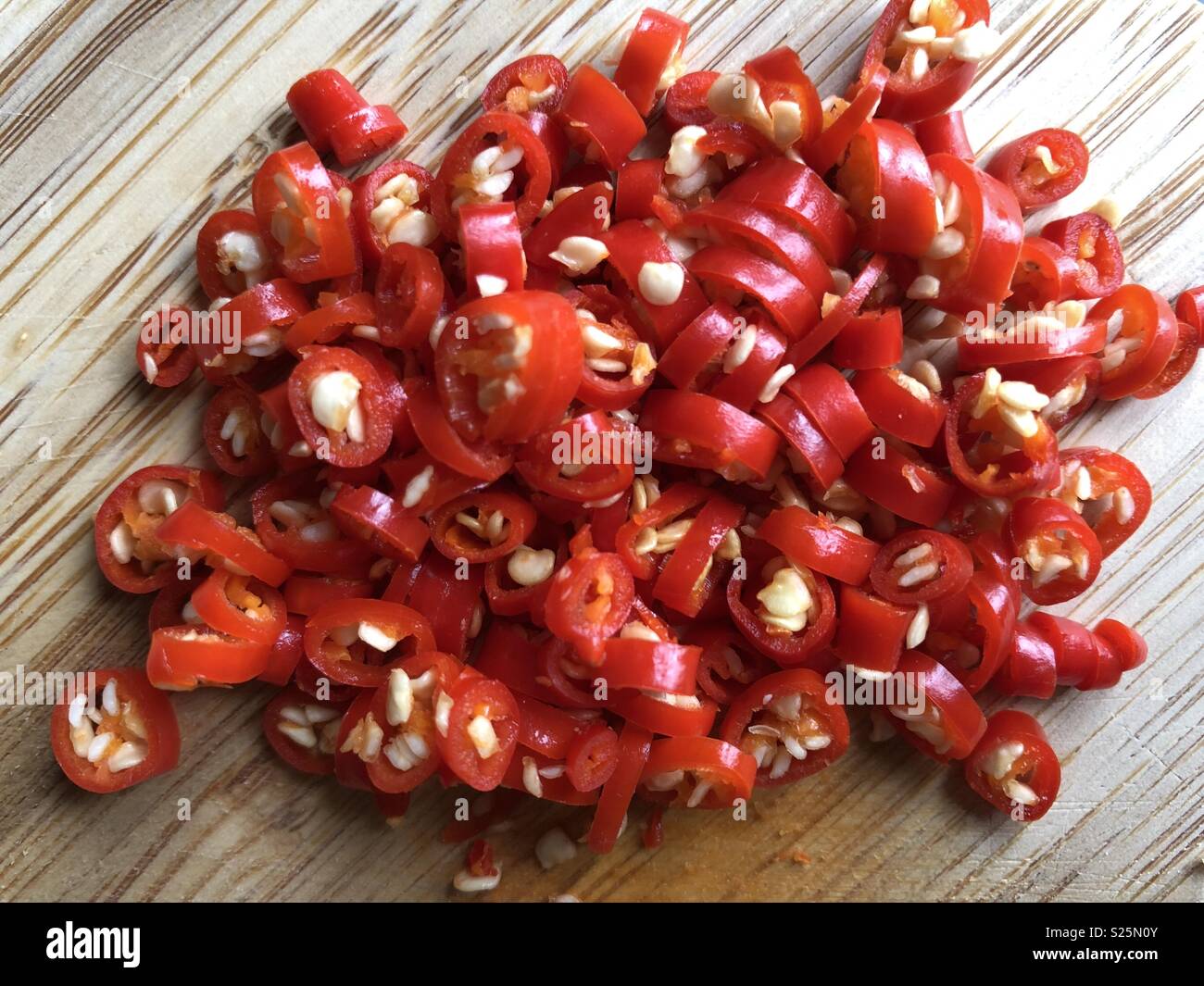 Chopped red chillies on wooden chopping board Stock Photo