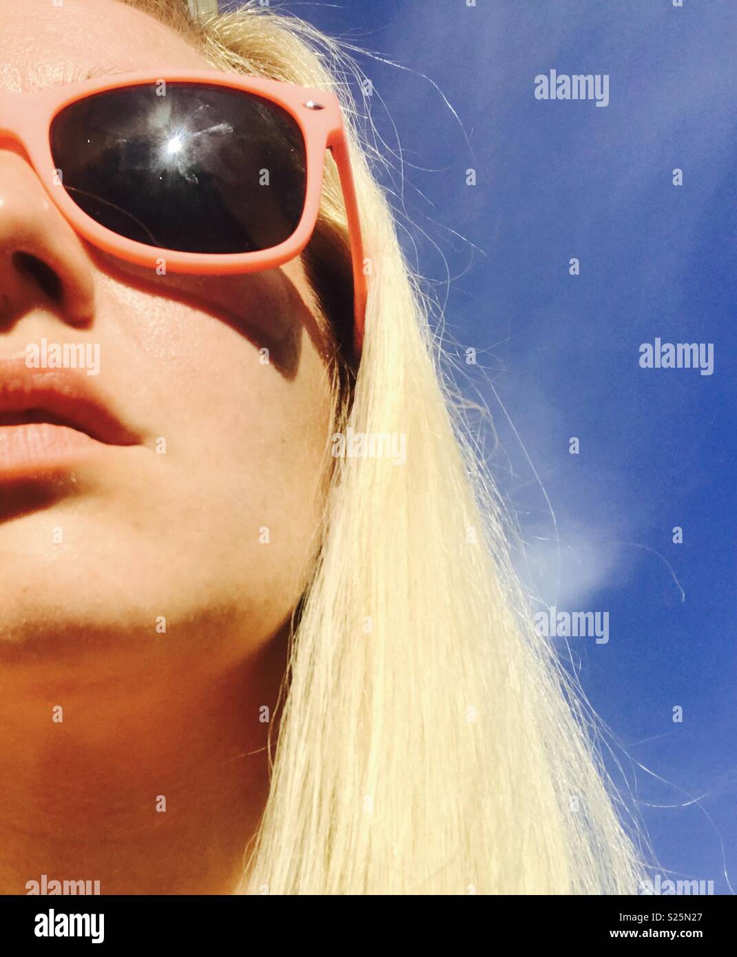 Platinum blonde hair woman wearing sunglasses against a summer blue sky. Stock Photo