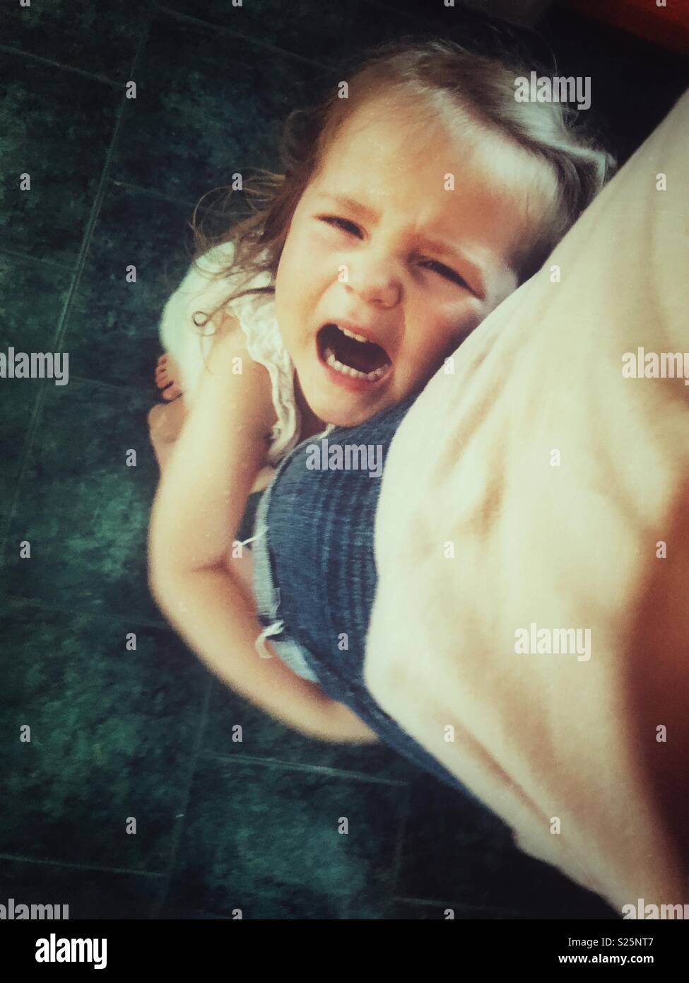 Toddler girl with arms around Mother’s leg crying during a temper tantrum - Smartphone Captured Stock Image