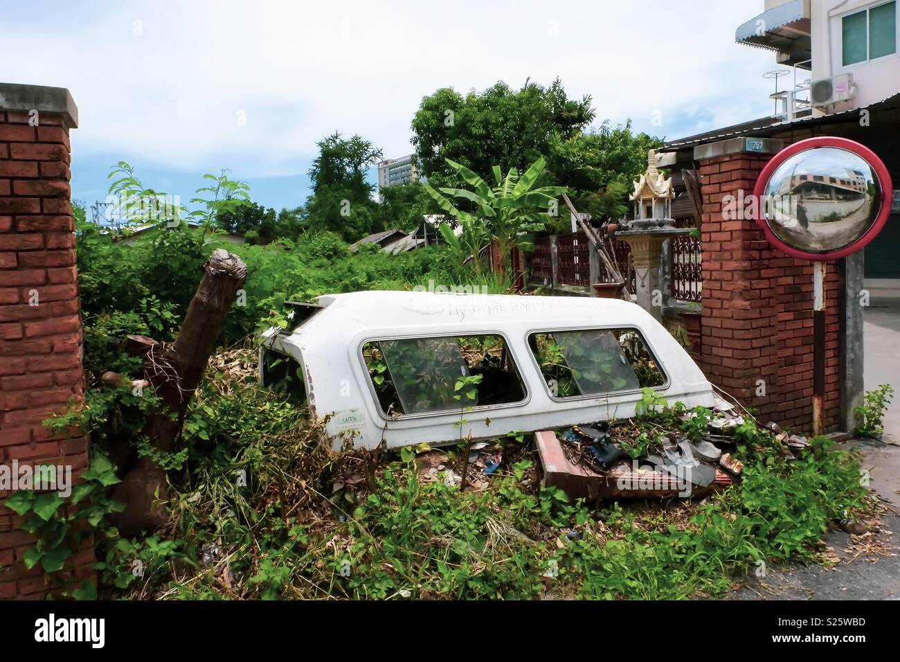 Old car parts by the side of the road.. Its common for rubbish to be left by the side of the road in Thailand but these parts seem to fit in nicely with their surroundings. Stock Photo