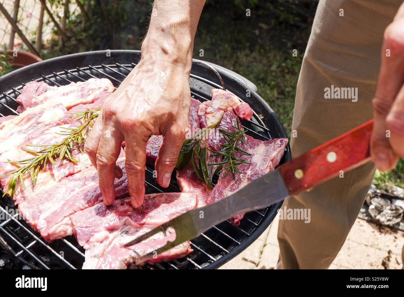 Grilling cow meat outdoors in a rounded small barbecue Stock Photo