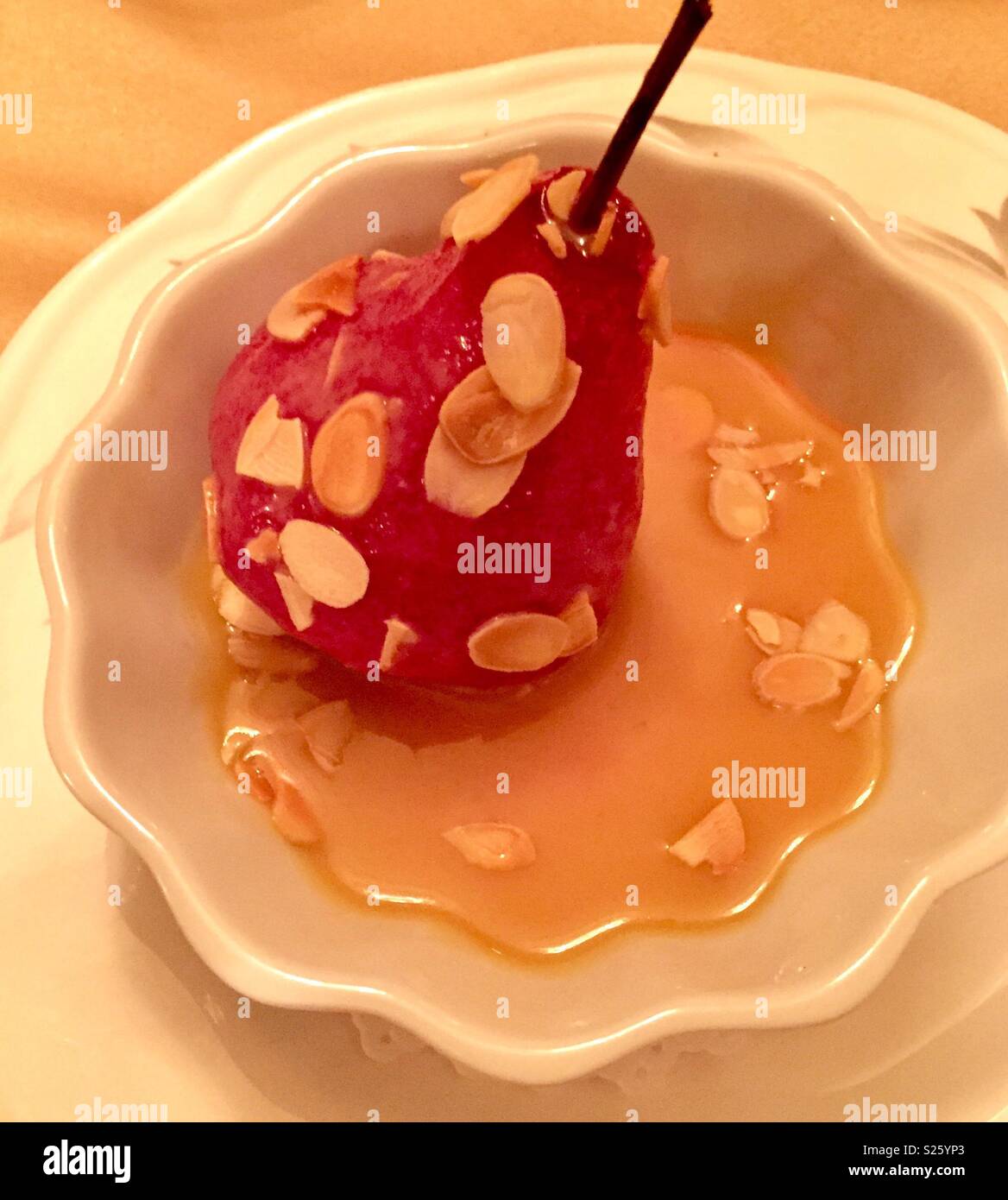 Poached pear with almonds and caramel syrup in a bowl. Delicious healthy dessert with fruits - Smartphone Captured Stock Image