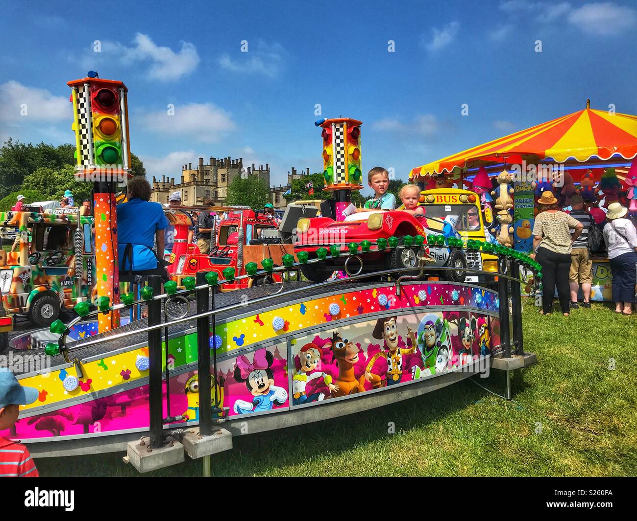 Fairground rides, children on a Merry-go-round, and a side stall game at the annual Sherborne Castle Country Fair, Sherborne, Dorset, England - Smartphone Captured Stock Image