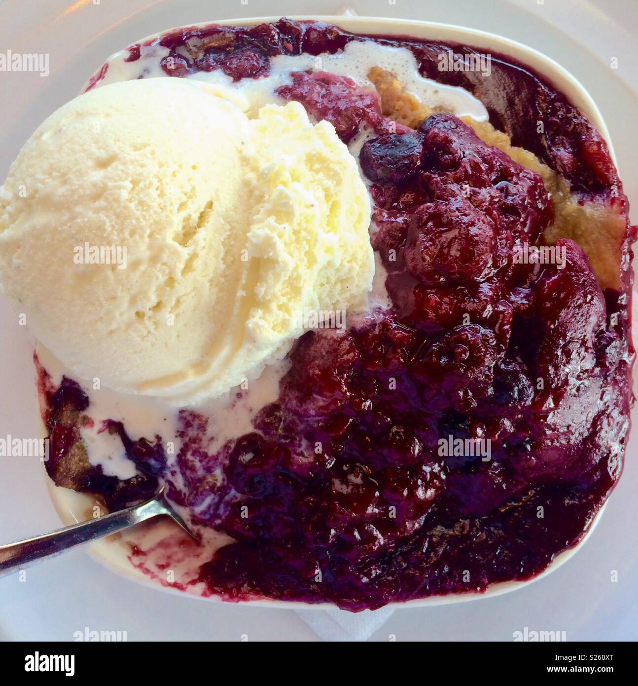 Dessert of warm mixed berry cobbler a la mode with vanilla ice cream
