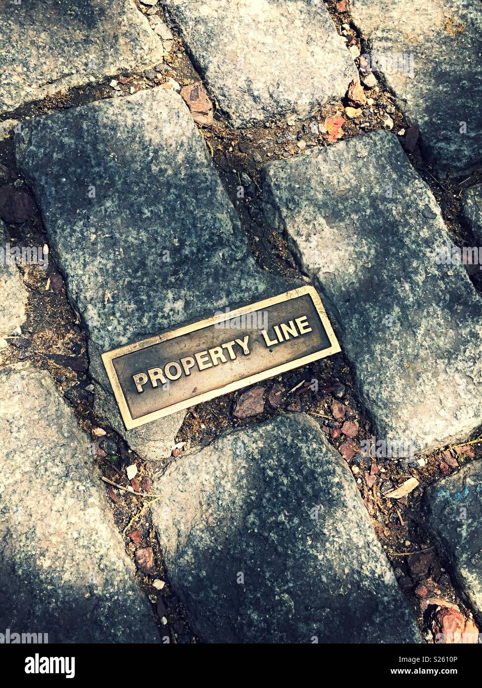 Property line brass marker on a cobblestone street, lower Manhattan, NYC, USA - Smartphone Captured Stock Image