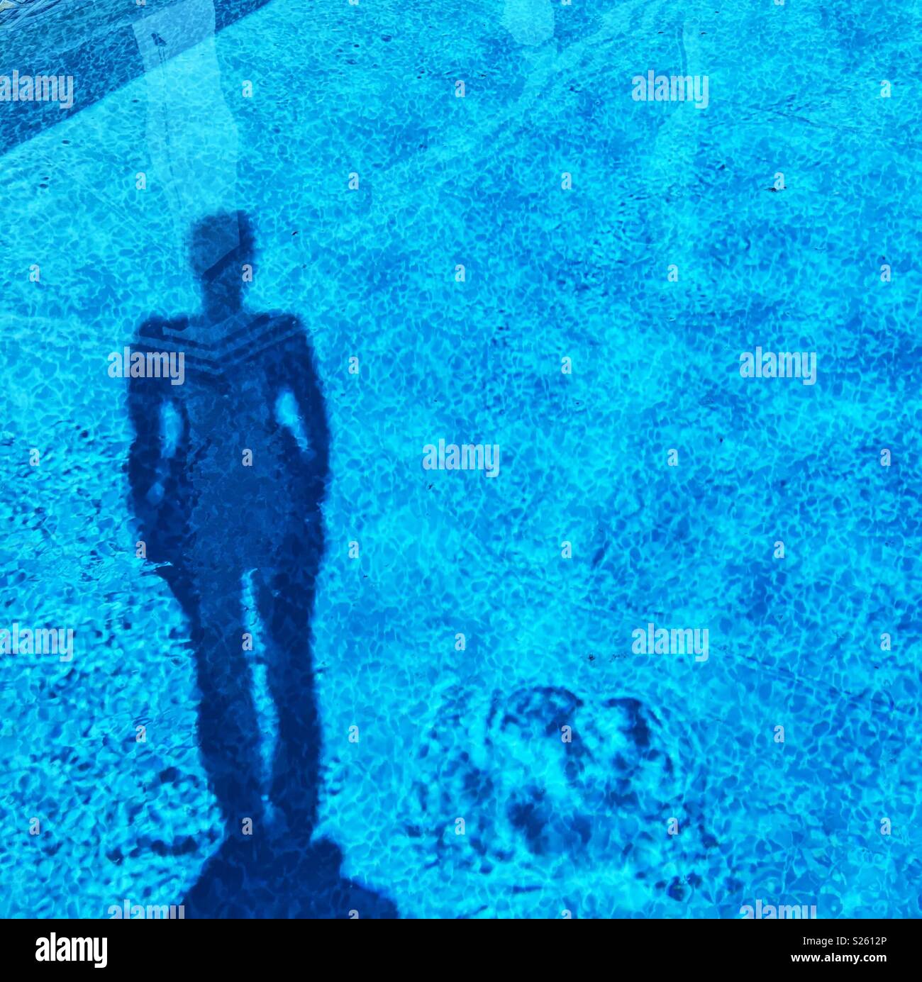 Shadow of a woman standing on diving board reflecting in an outdoor swimming pool. Square crop. - Smartphone Captured Stock Image