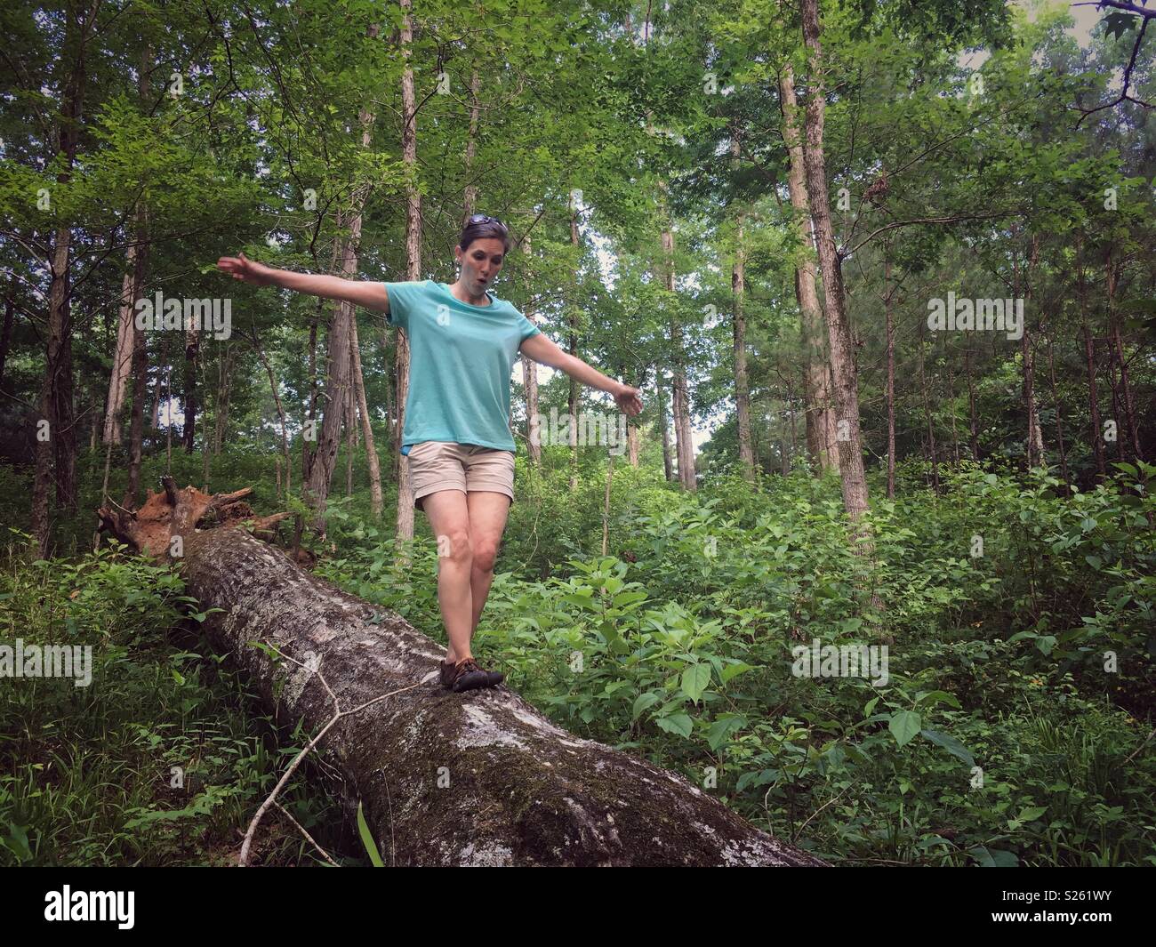 Woman balances on log in forest - Smartphone Captured Stock Image
