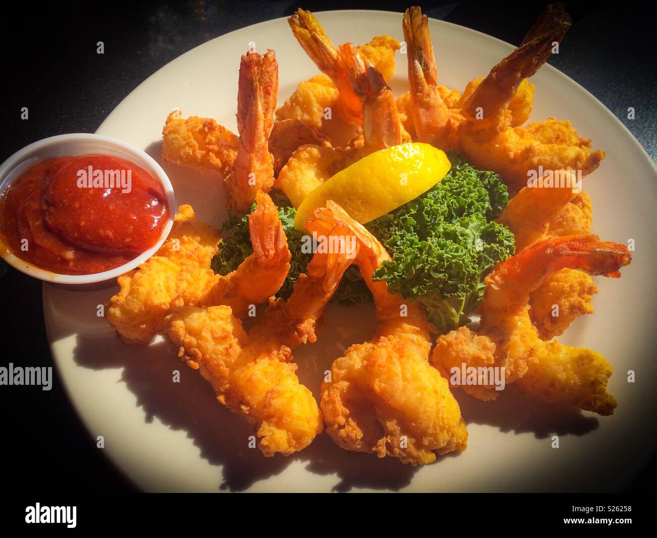 Golden fried shrimp with lemon and cocktail sauce, vignette filter applied Stock Photo