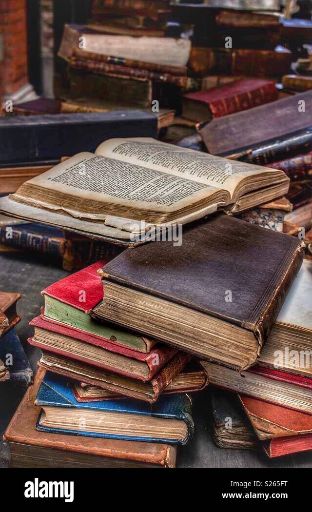 Old fashioned books on a market stall with one book open on a page
