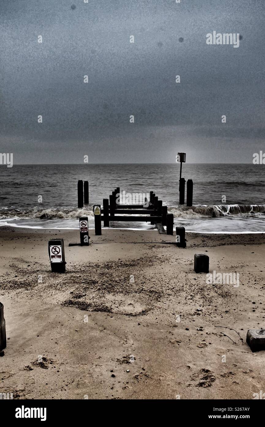 Waves breaking on a beach by wooden posts Stock Photo - Alamy