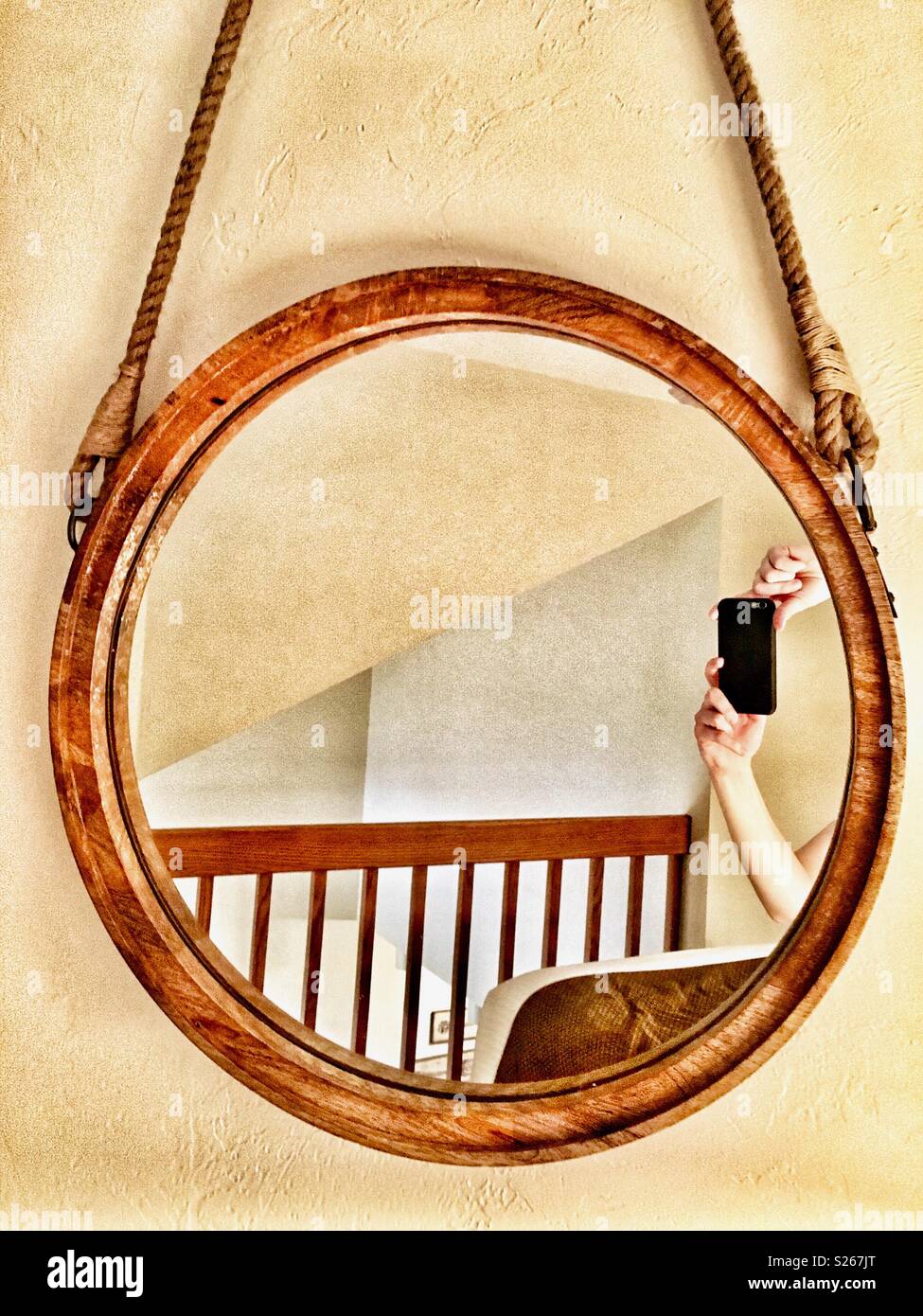 Person taking selfie of hands in a round mirror by a balcony Stock Photo