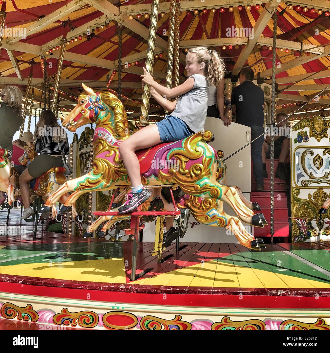 Fairground rides, young girl on merry-go-round at Sherborne Castle Country Fair, Sherborne, Dorset, England Stock Photo
