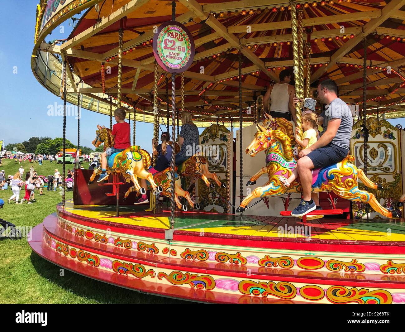 Fairground rides, father & daughter on merry-go-round at Sherborne Castle Country Fair, Sherborne, Dorset, England - Smartphone Captured Stock Image
