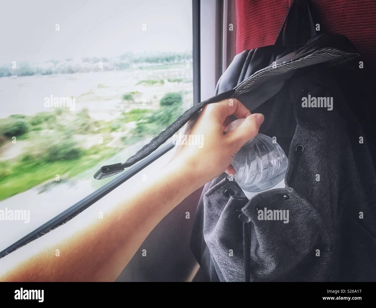 A hand reaches for water bottle in a fat train - Smartphone Captured Stock Image