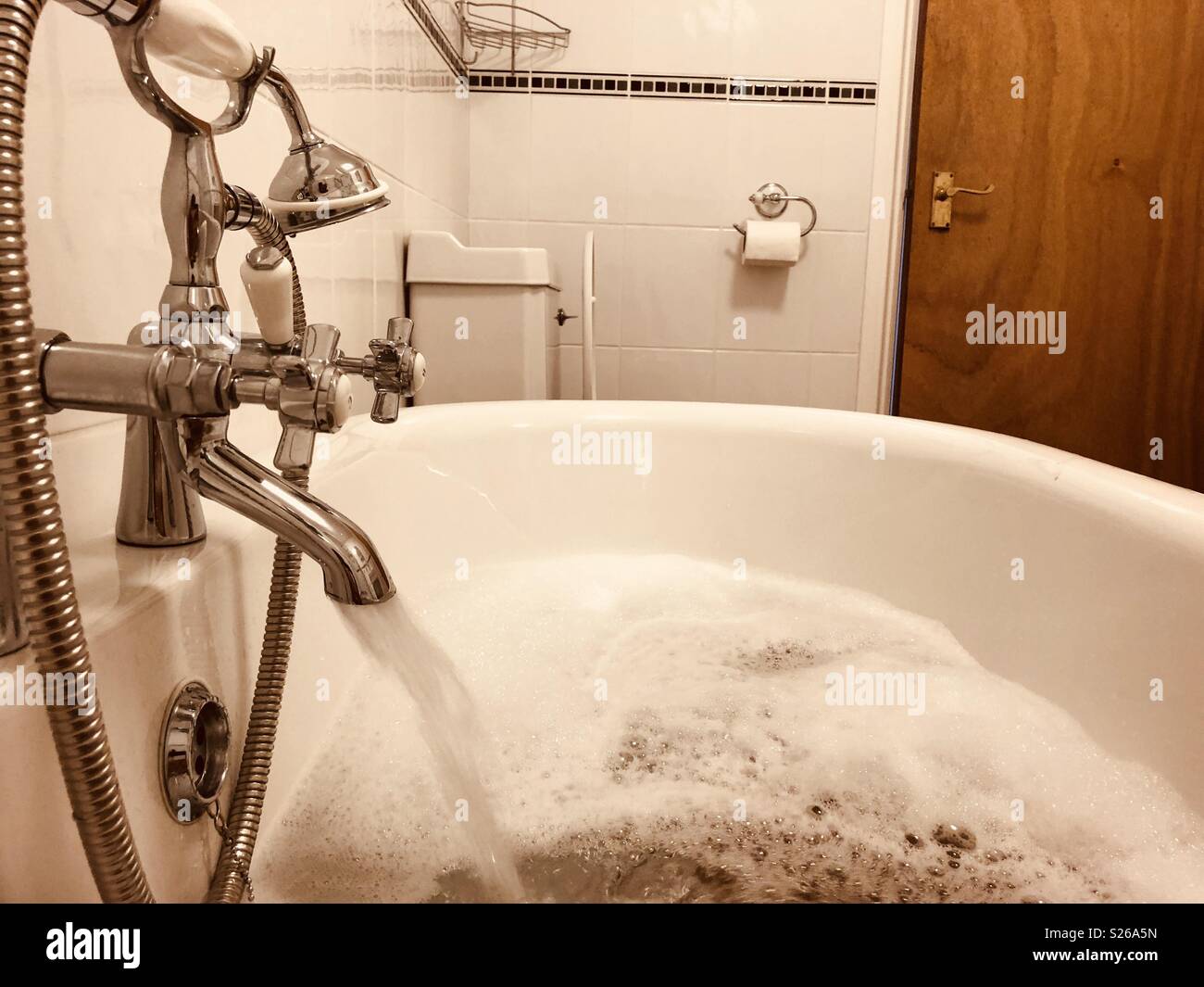 Water pouring from a tap into a bath tub Stock Photo