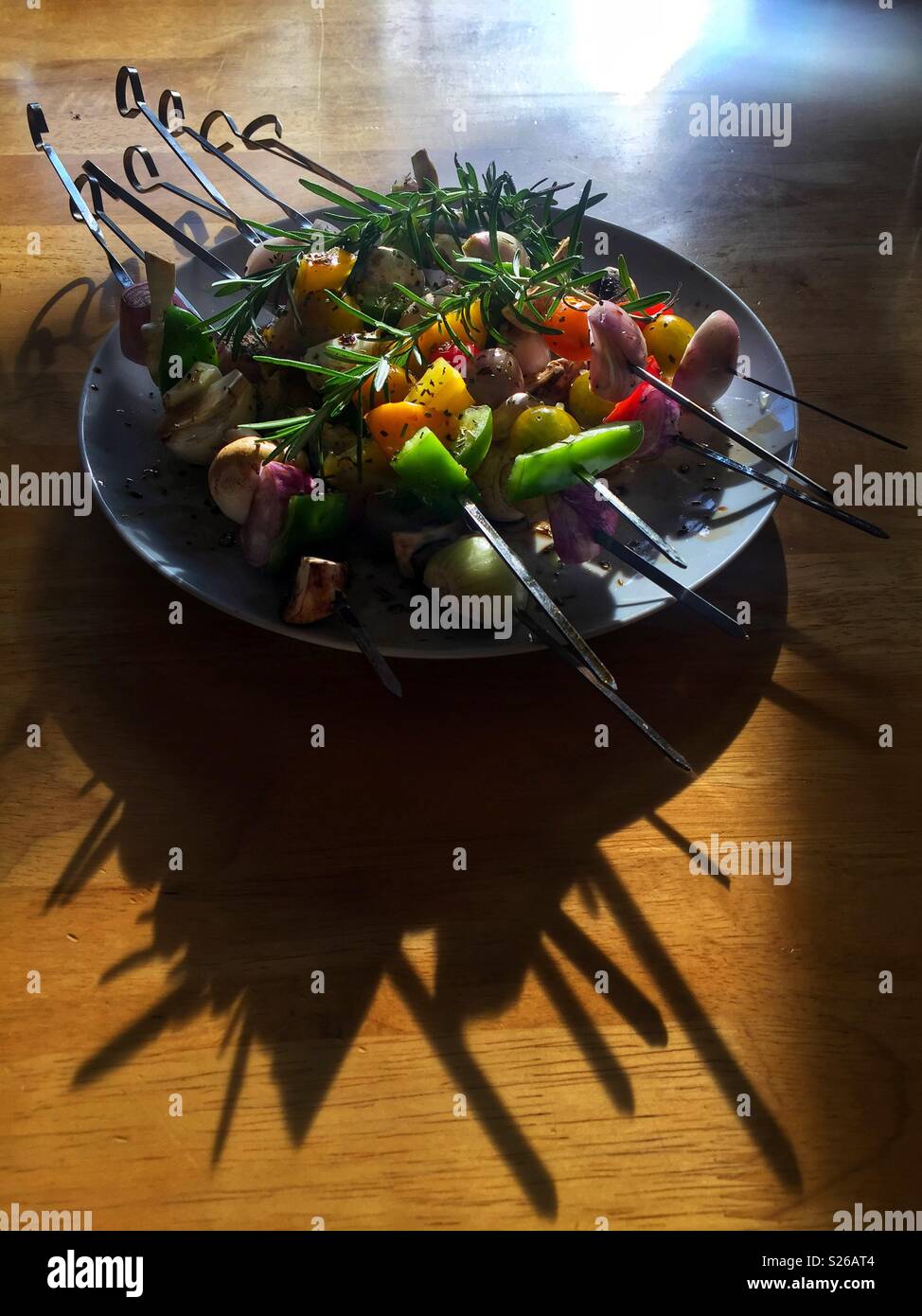 Vegetarian kebabs on skewers ready for the barbecue, on a table with the summer sun casting long dark shadows - Smartphone Captured Stock Image