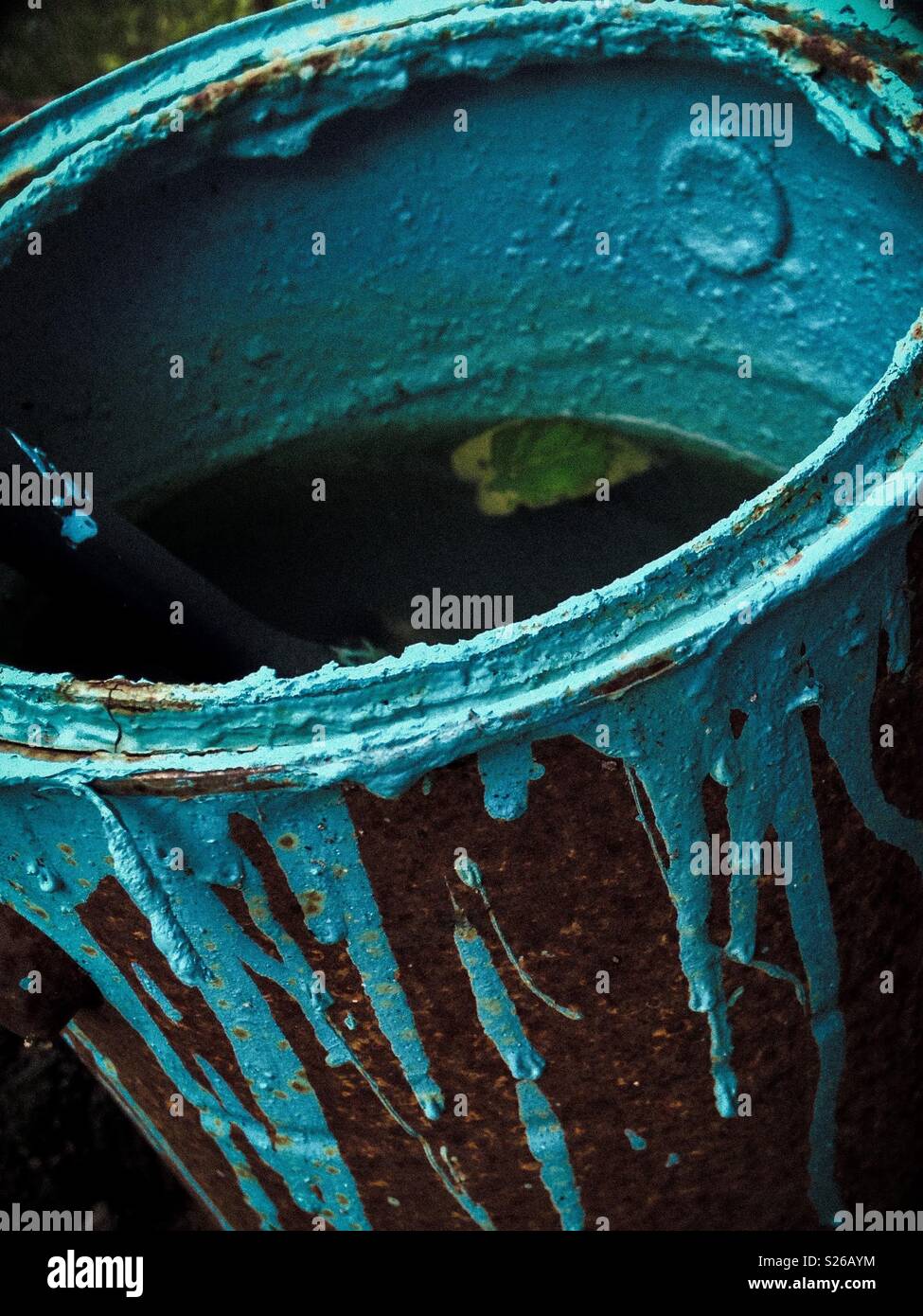 Shadowed photo of rusted paint can splattered with aqua paint now