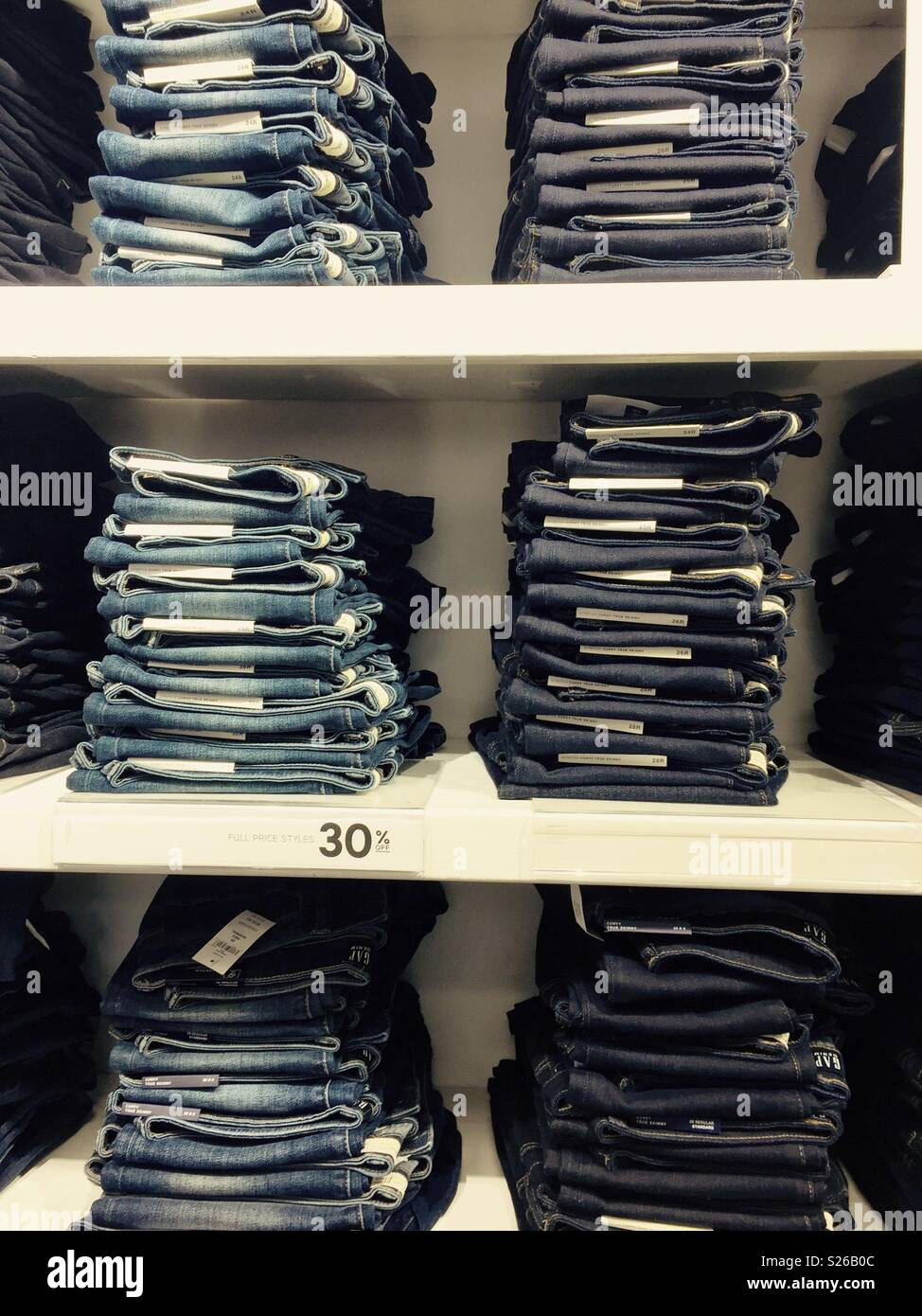 Stacks of denim jeans on shelves in a display in a clothes shop Stock