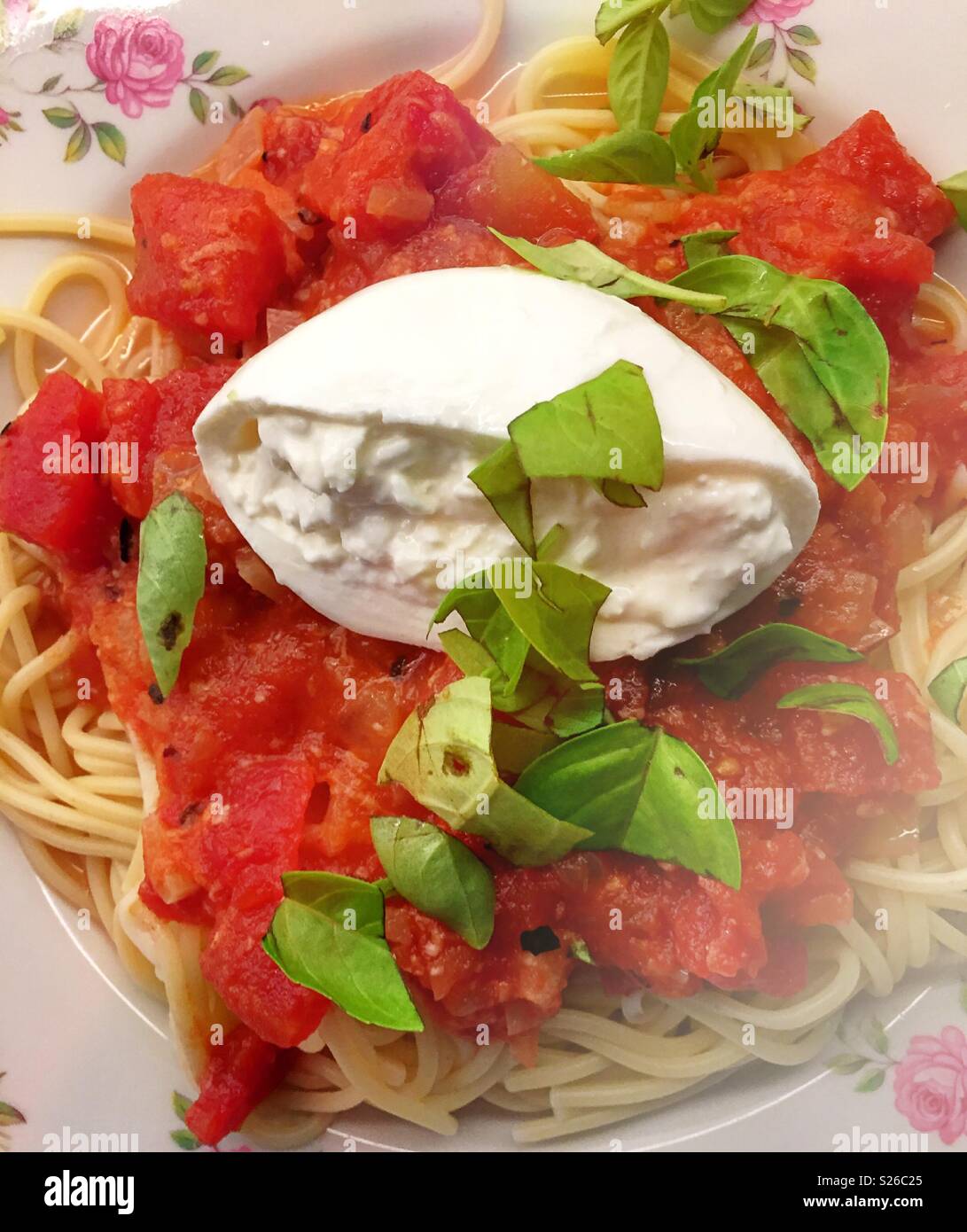 Burrata cheese and fresh basil on top of marinara sauce on pasta Stock