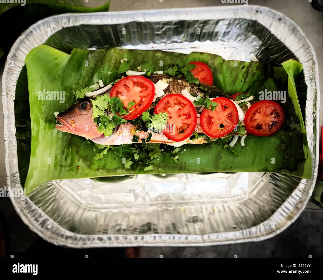 A red snapper baked on banana leafs with tomatoes, onion and coriander in Todos Santos, Baja California, Mexico - Smartphone Captured Stock Image