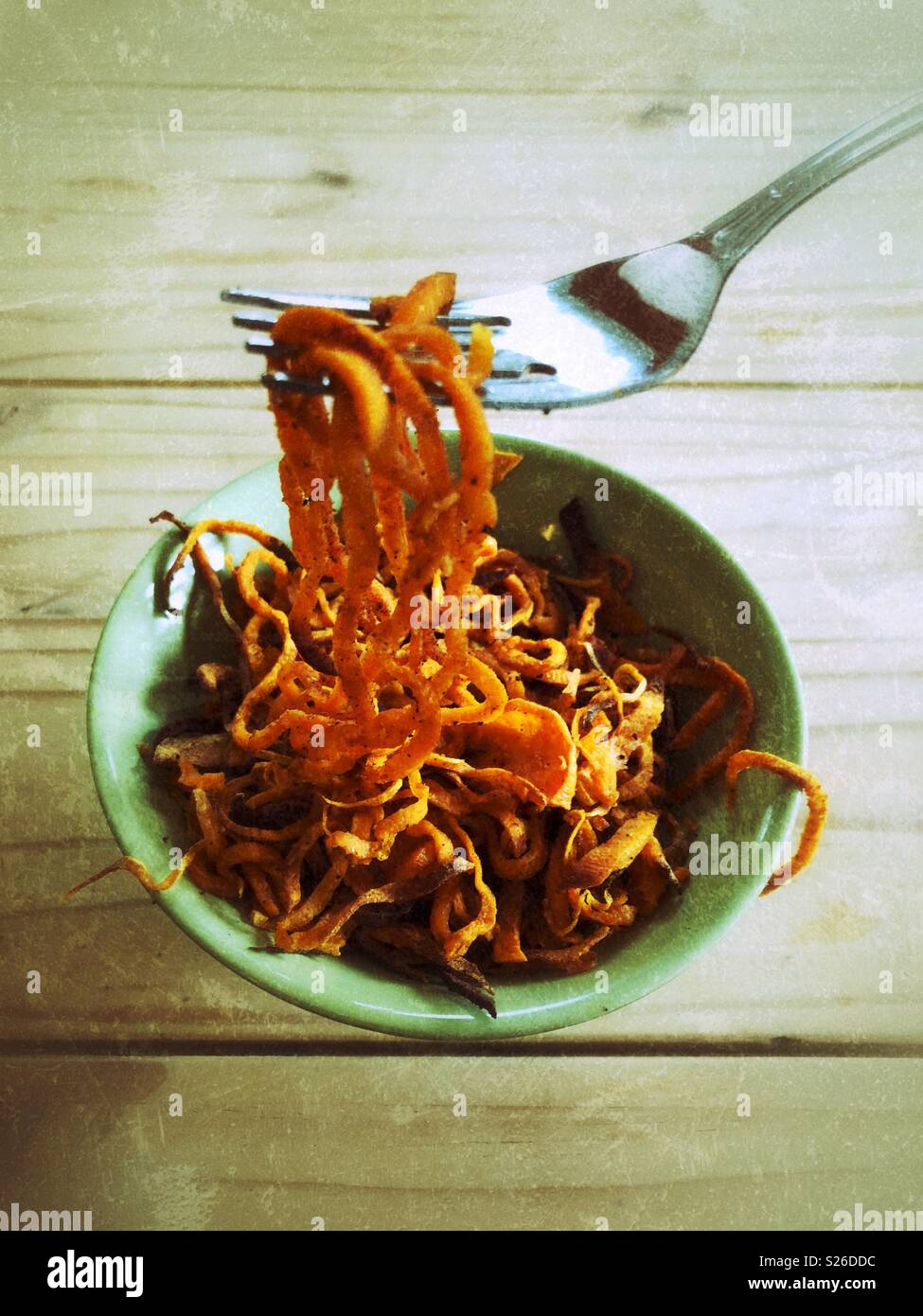 Eating bowl full of spiralized sweet potato noodles with a fork from perspective of person - Smartphone Captured Stock Image