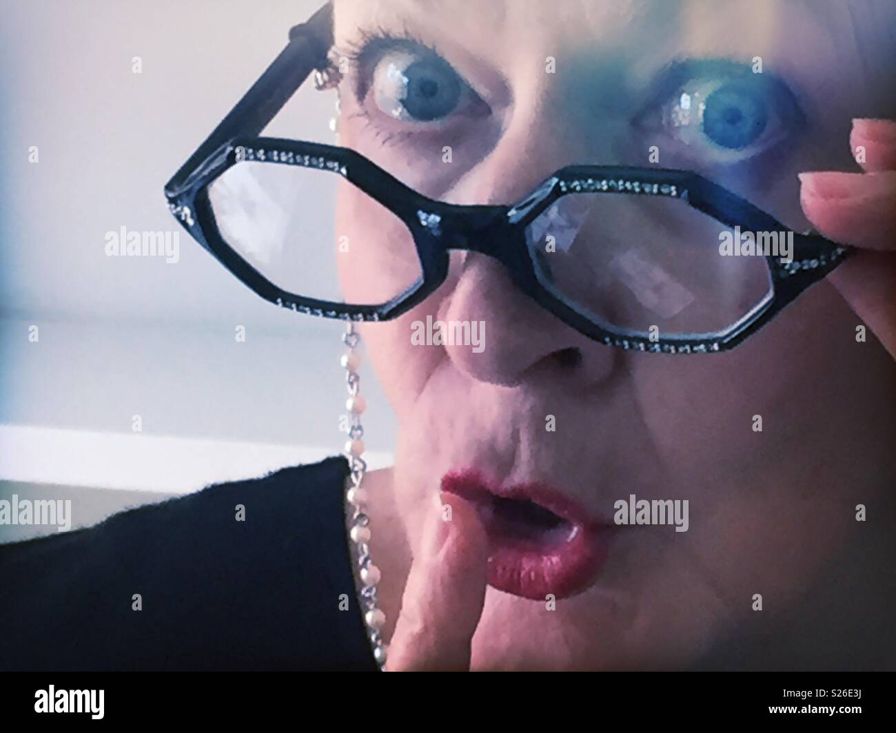 Woman librarian with the rhinestone eyeglasses signaling hush with her finger, United States Stock Photo