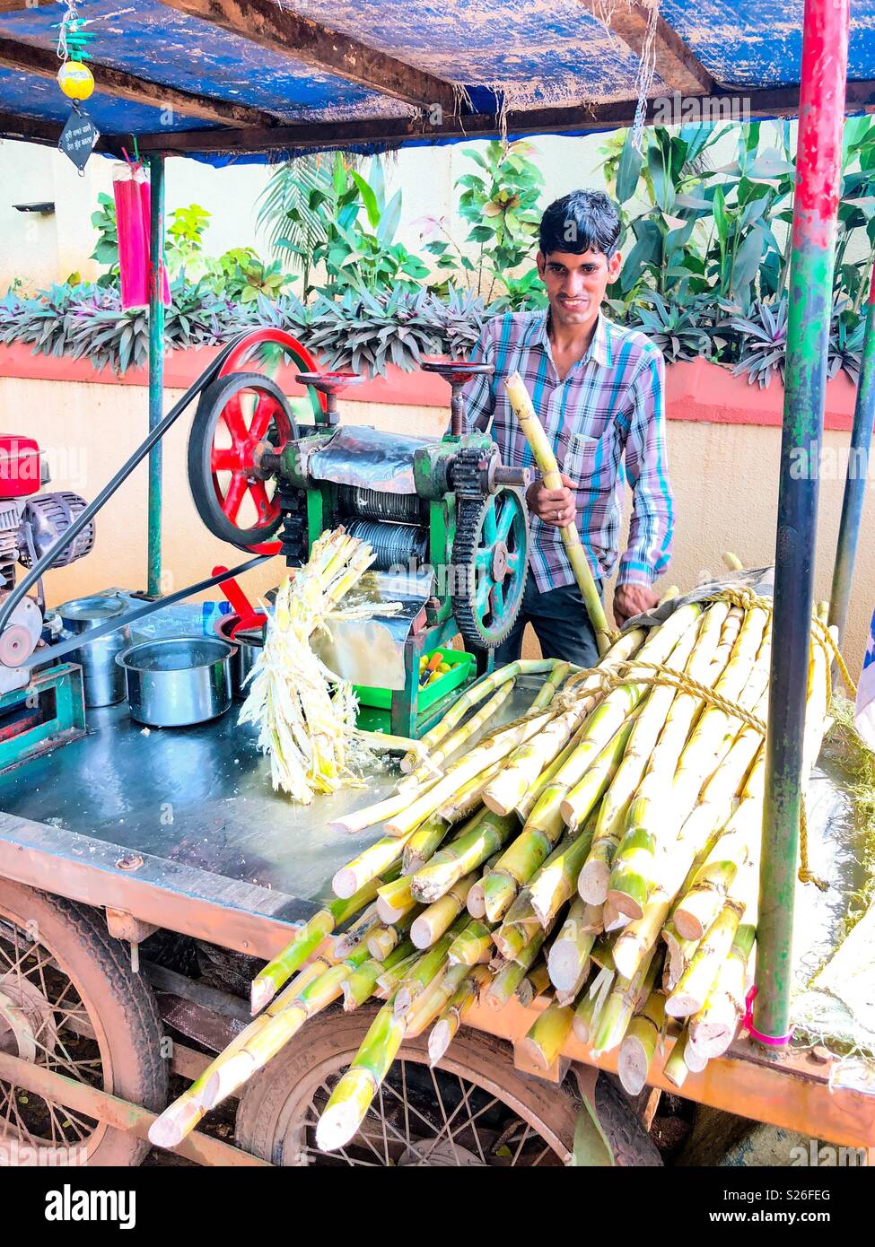 A gentleman working a sugarcane drink machine from a roadside vehicle in India Stock Photo