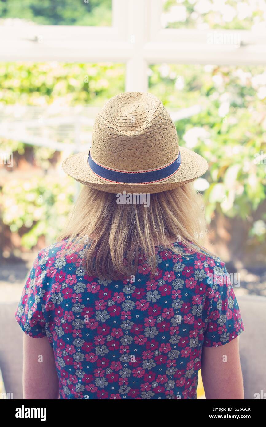 Rear view of a young girl in a pretty, floral dress and straw hat Stock Photo