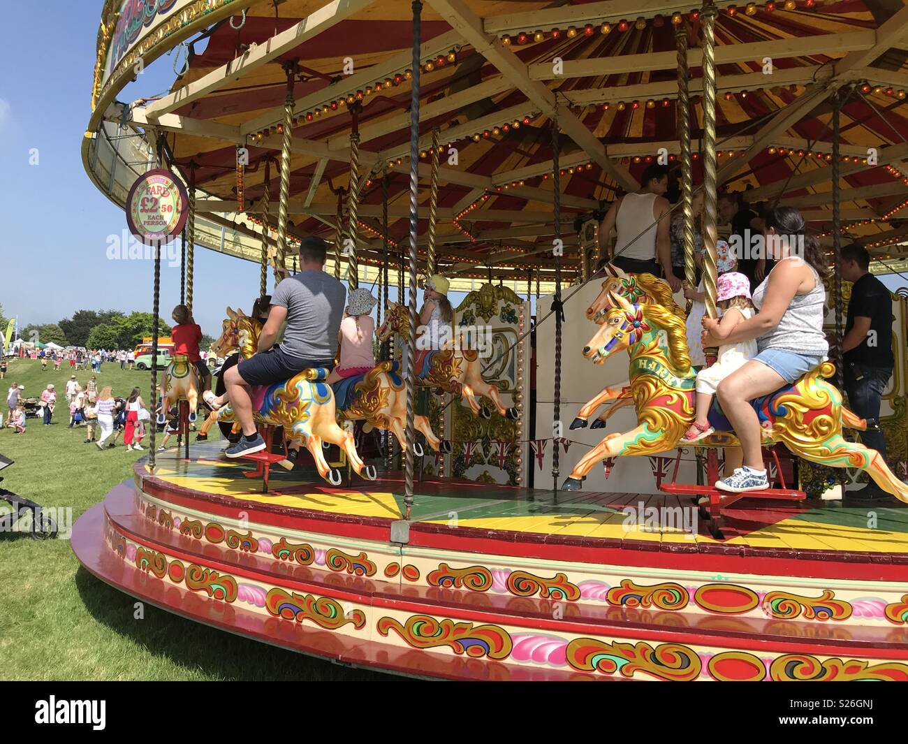 Parents and kids enjoying a ride on a fairground  carousel on a sunny, summer day. - Smartphone Captured Stock Image