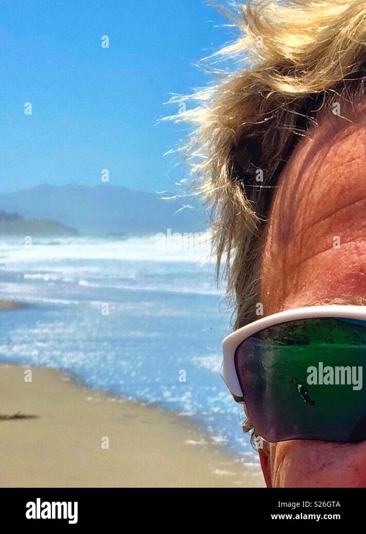 https://c8.alamy.com/comp/S26GTA/blond-surfer-with-sunglasses-on-a-northern-california-beach-in-summer-with-coastal-mountains-sand-and-surf-S26GTA.jpg