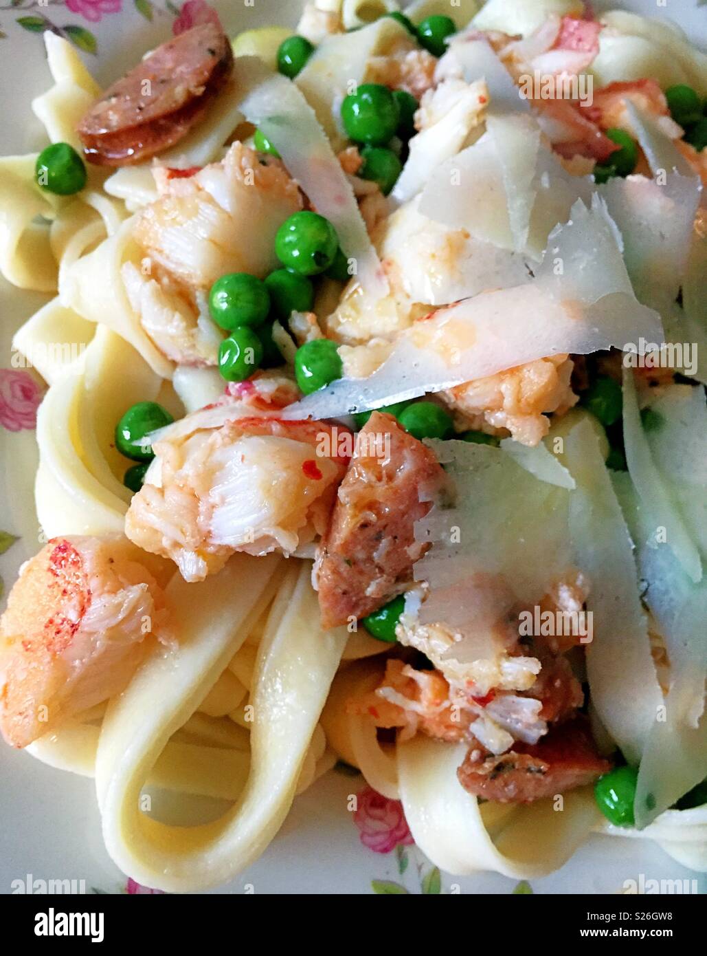 Gourmet lobster fettuccine dish with spring peas and sausage, close up - Smartphone Captured Stock Image