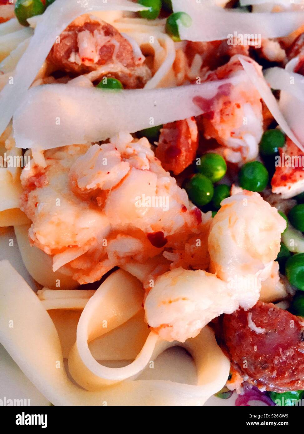 Gourmet lobster fettuccine dish with spring peas and sausage, close up - Smartphone Captured Stock Image