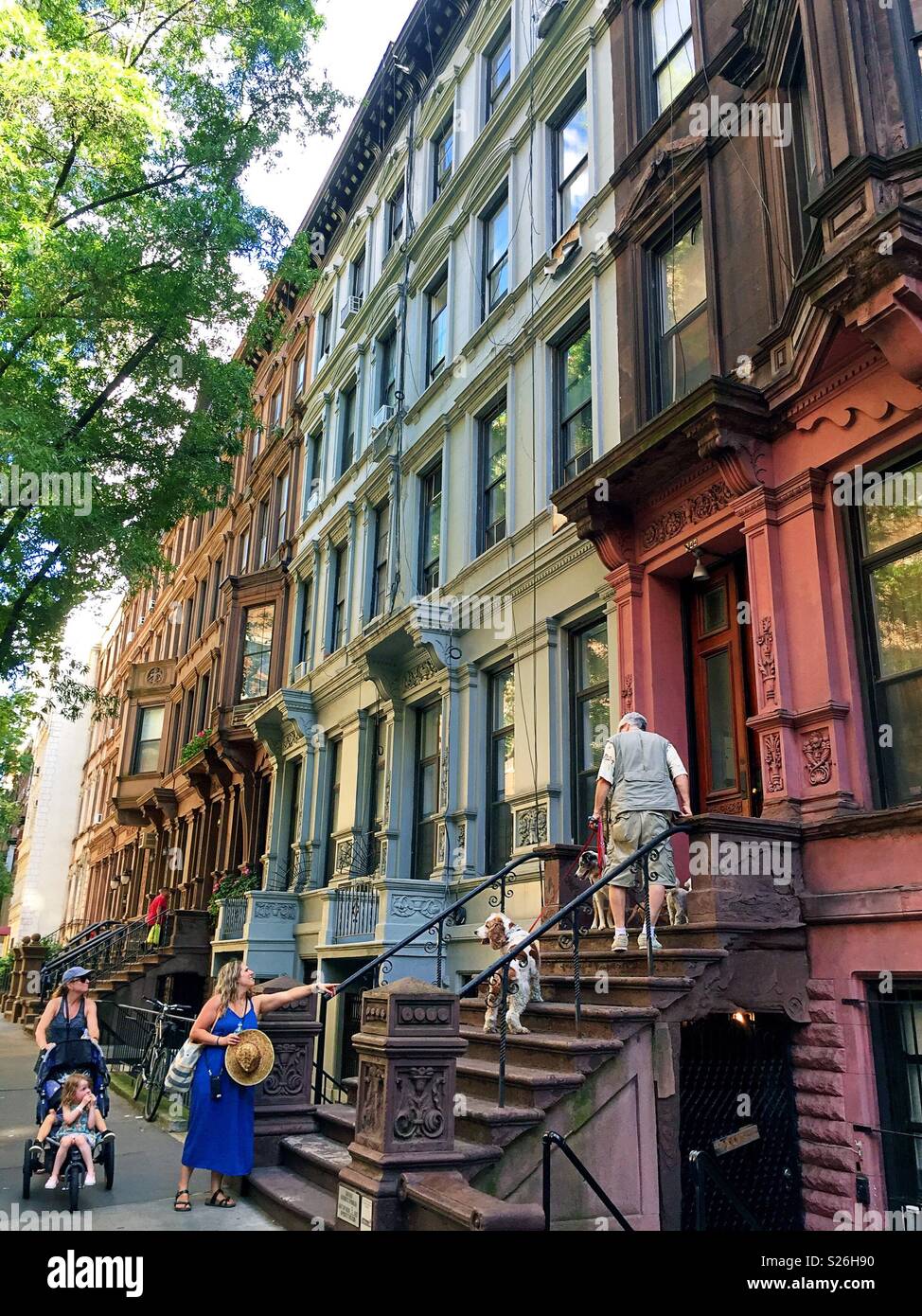 Neighborhood scene of people interacting on front stoops brownstones