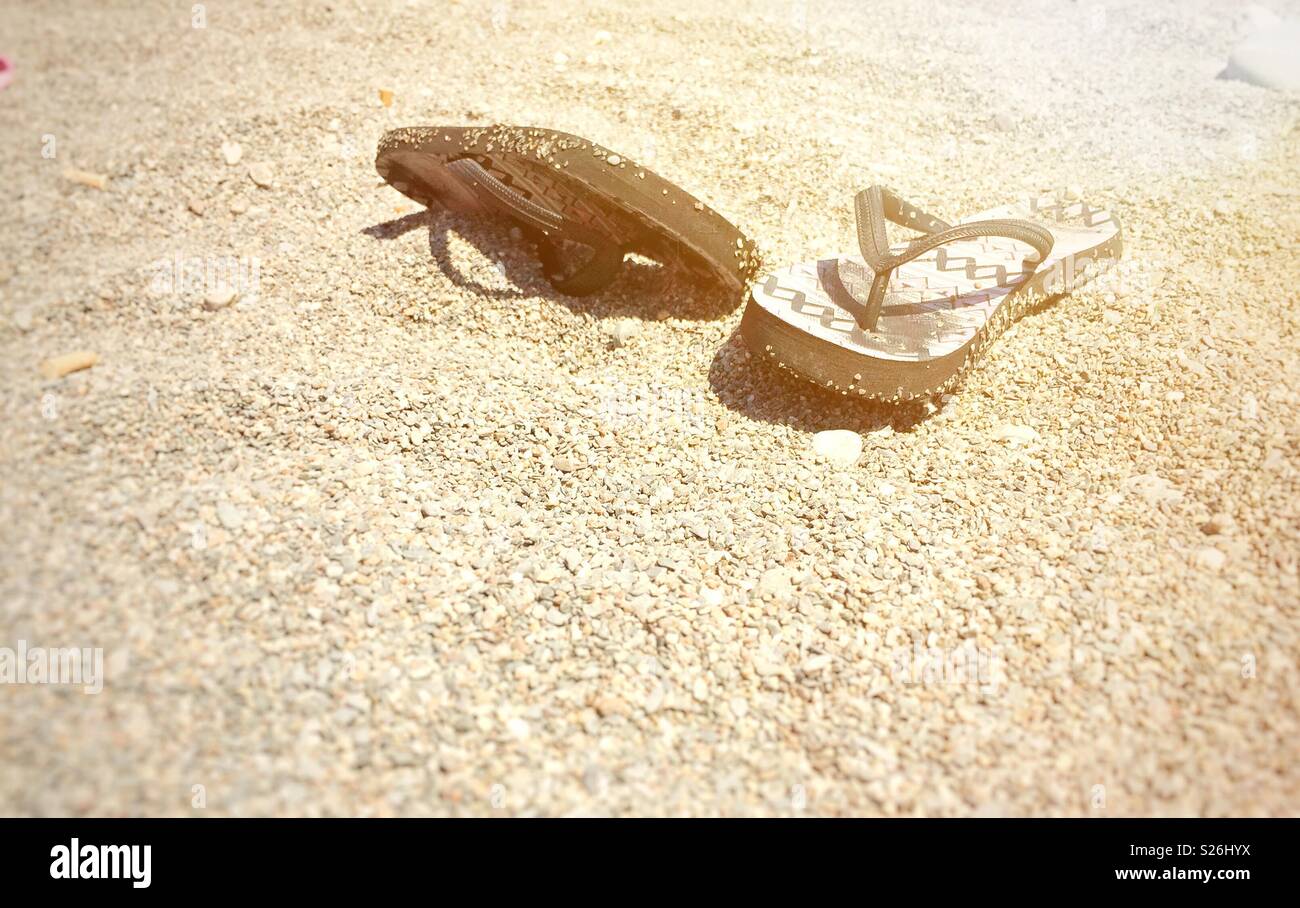 a pair of flip-flops on a stony beach - Smartphone Captured Stock Image