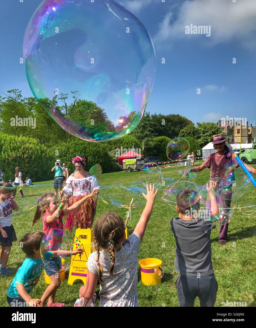 Bubbleman creating soap bubbles, and children trying to pop them, Sherborne Castle Country Fair, Sherborne, Dorset, England - Smartphone Captured Stock Image