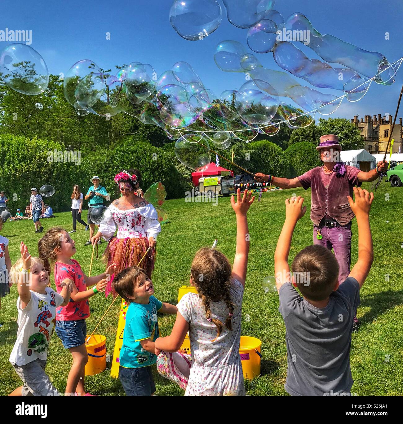 Bubbleman and Bubble Faerie creating soap bubbles, and children trying to pop them, Sherborne Castle Country Fair, Sherborne, Dorset, England Stock Photo