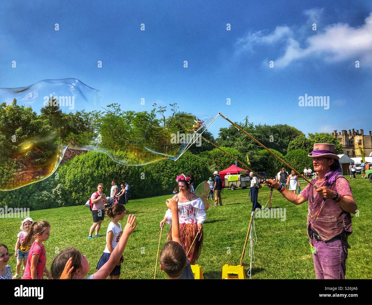 Bubbleman and Bubble Faerie creating soap bubbles, and children trying to pop them, Sherborne Castle Country Fair, Sherborne, Dorset, England - Smartphone Captured Stock Image