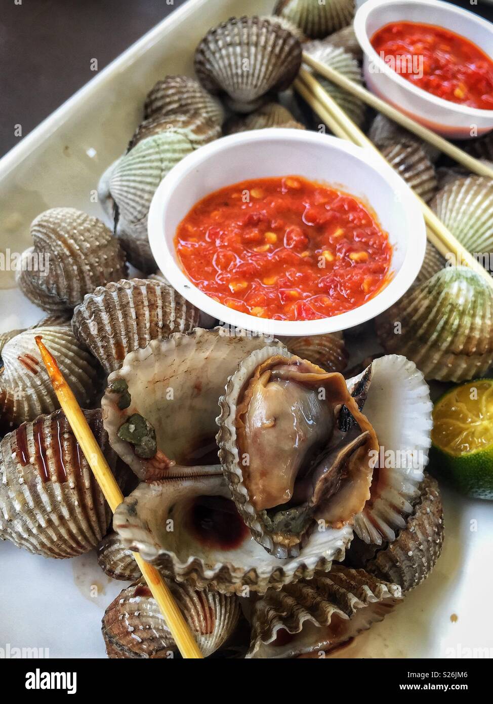 Clams and chilli sauce at East Coast Lagoon Food Village, a hawker food market in Singapore Stock Photo