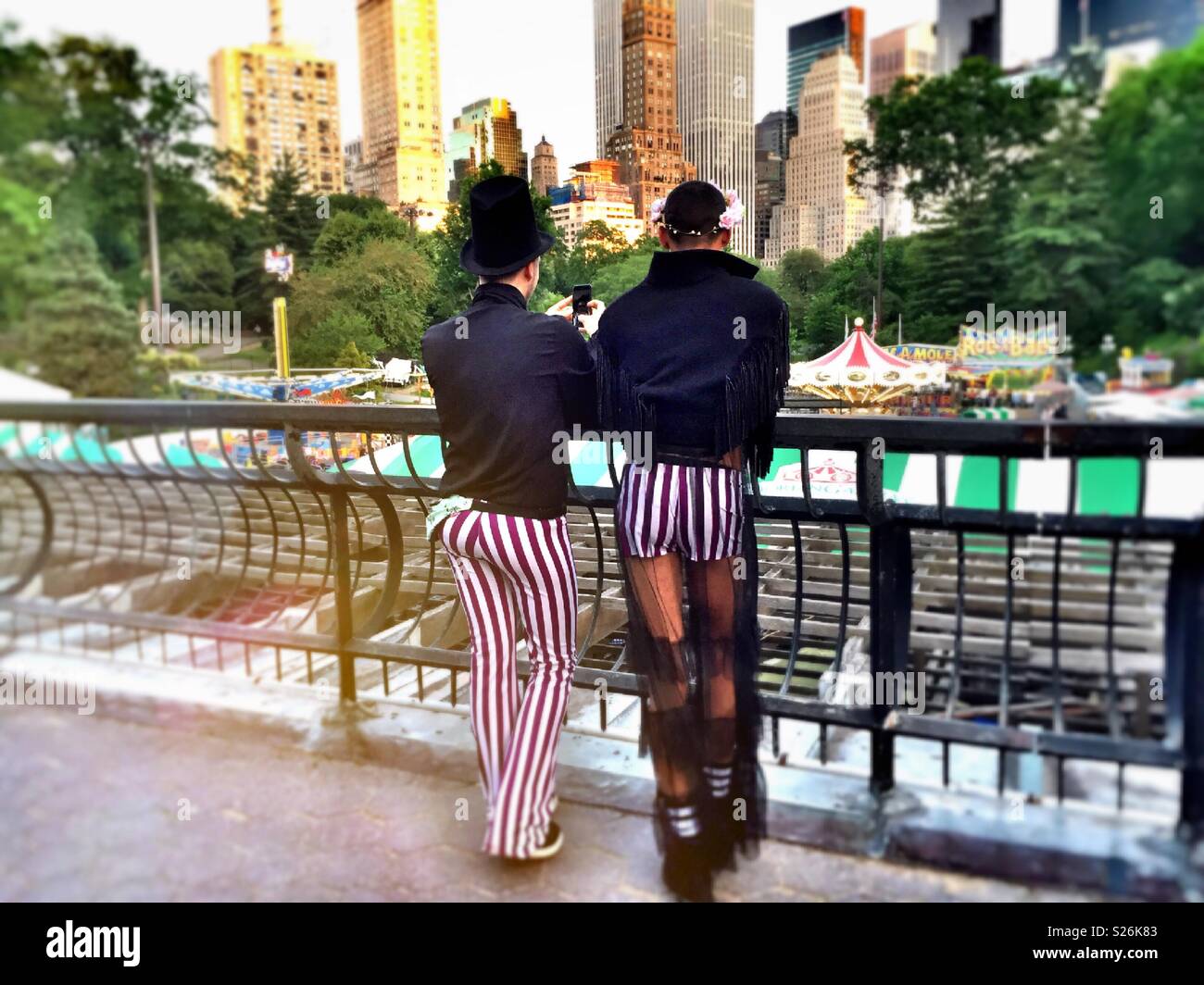 Unconventional male couple overlooking Victorian gardens amusement park, Central Park NYC USA Stock Photo