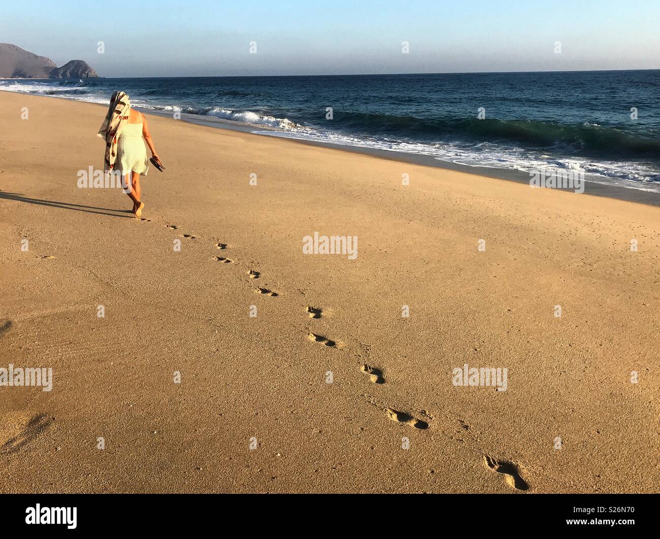 A woman walks in the beach in the Pacific ocean coast in Todos Santos, Baja California, Mexico Stock Photo
