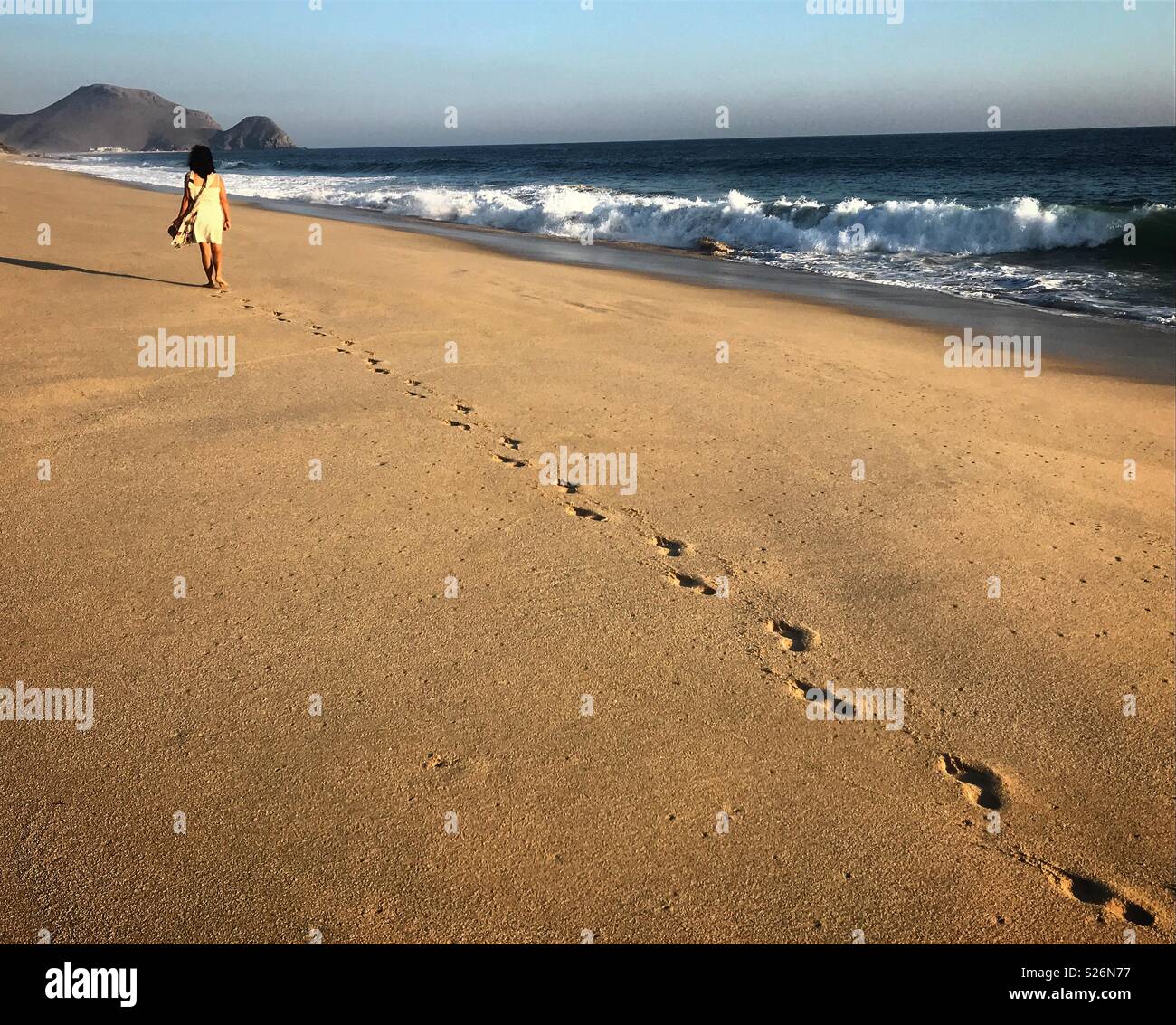 A tourist walks in a beach in Todos Santos, Baja California, Mexico - Smartphone Captured Stock Image