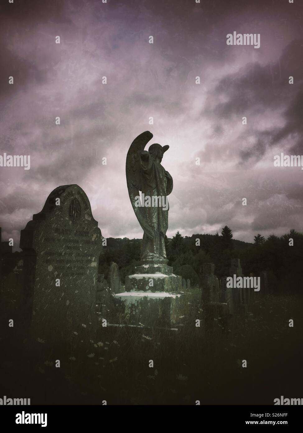 An eerie graveyard with gravestones and a spooky angel monument - Smartphone Captured Stock Image