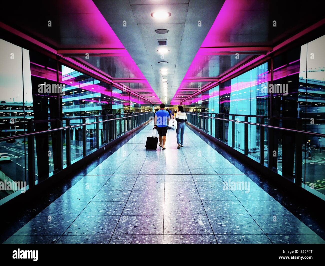 A walkway at an airport lit by pink neon lighting. - Smartphone Captured Stock Image