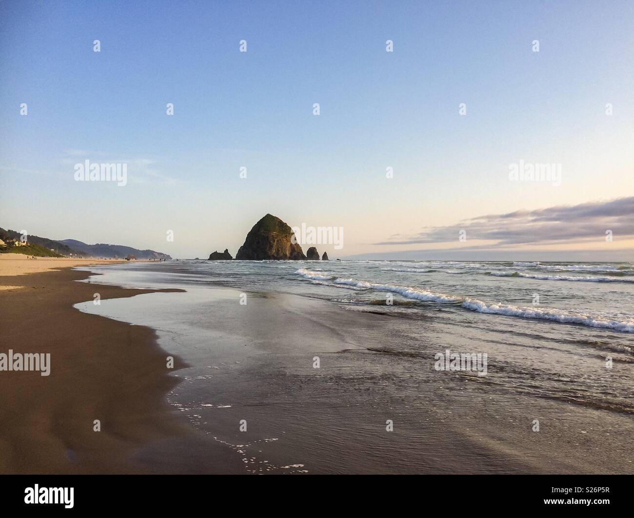 Remote view of Haystack Rock on late afternoon before sunset from the beach, Cannon Beach, Oregon Coast, USA. - Smartphone Captured Stock Image