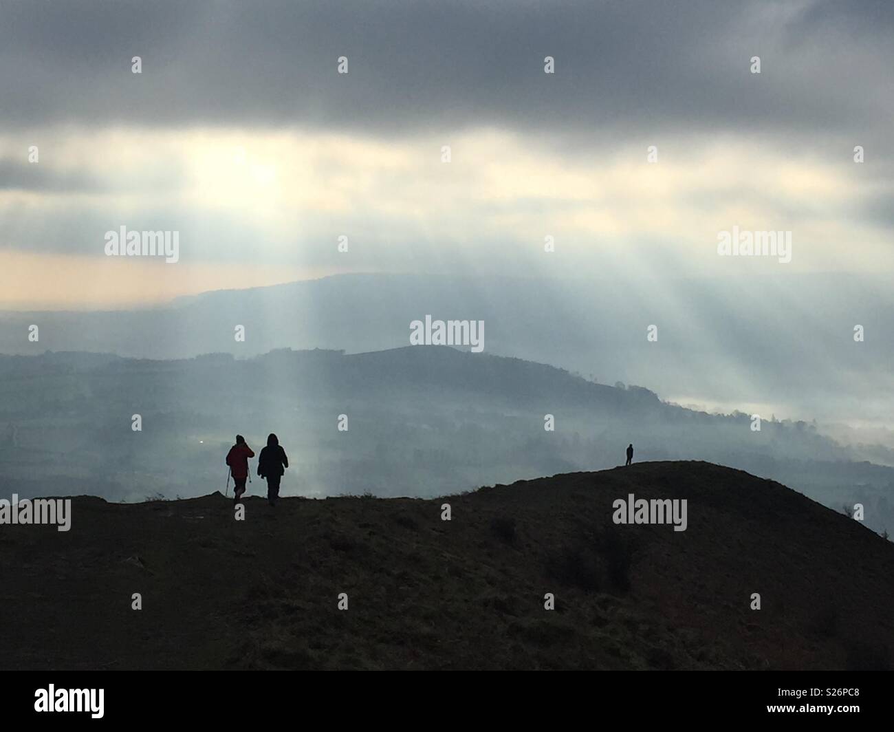Sun rays shine down on walkers silhouetted on the Skirrid Mountain, Brecon Beacons, near Abergavenny, Wales, UK. - Smartphone Captured Stock Image