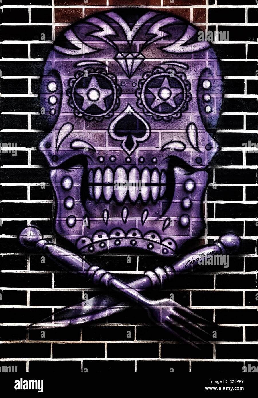 Skull and crossed-cutlery artwork on a restaurant wall at Cancun airport, Mexico. Artwork signed by Craig Fraser. - Smartphone Captured Stock Image