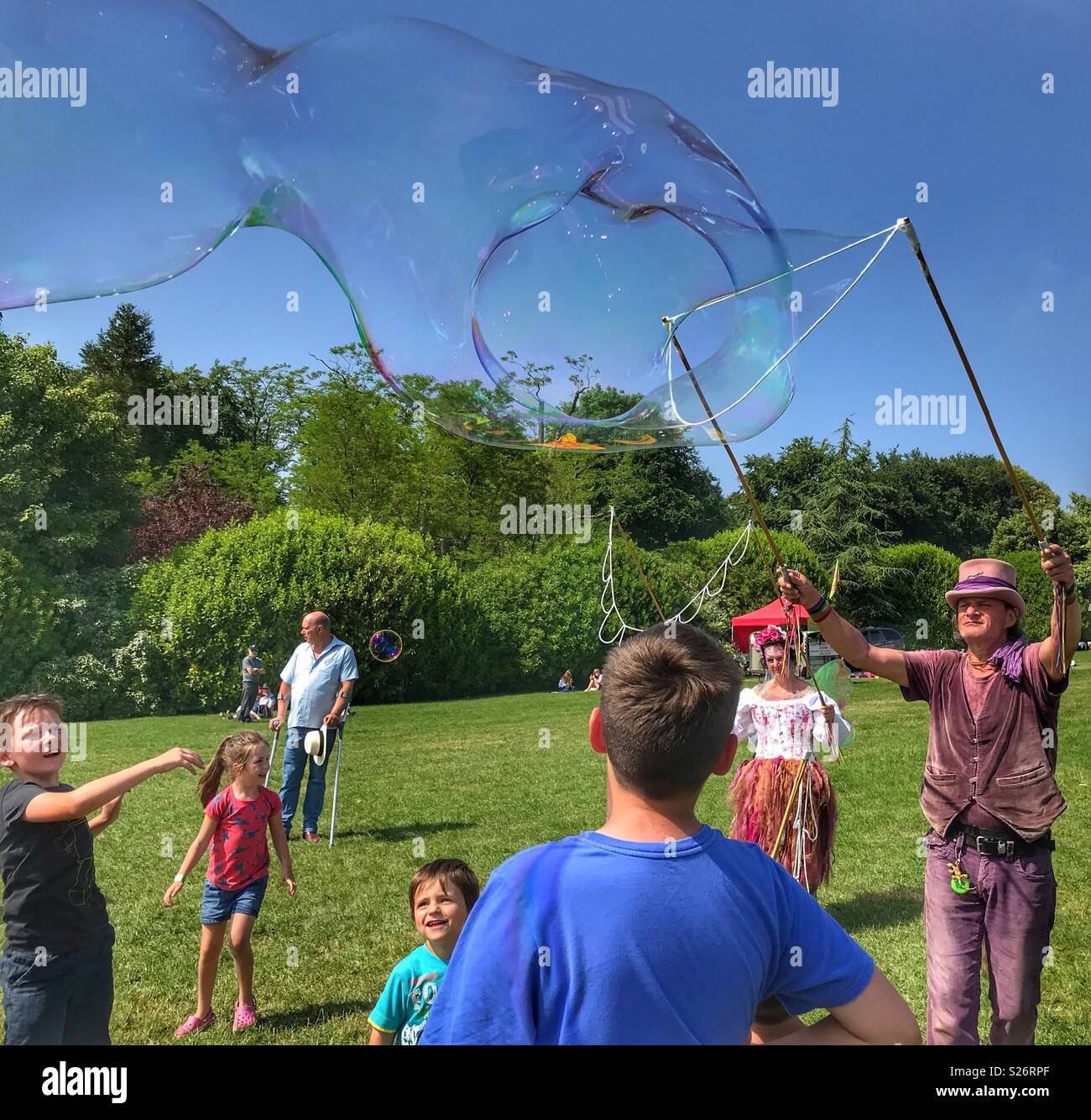 Man and woman creating huge soap bubbles, entertaining a group of children, Sherborne Castle Country Fair, Sherborne, Dorset, England - Smartphone Captured Stock Image