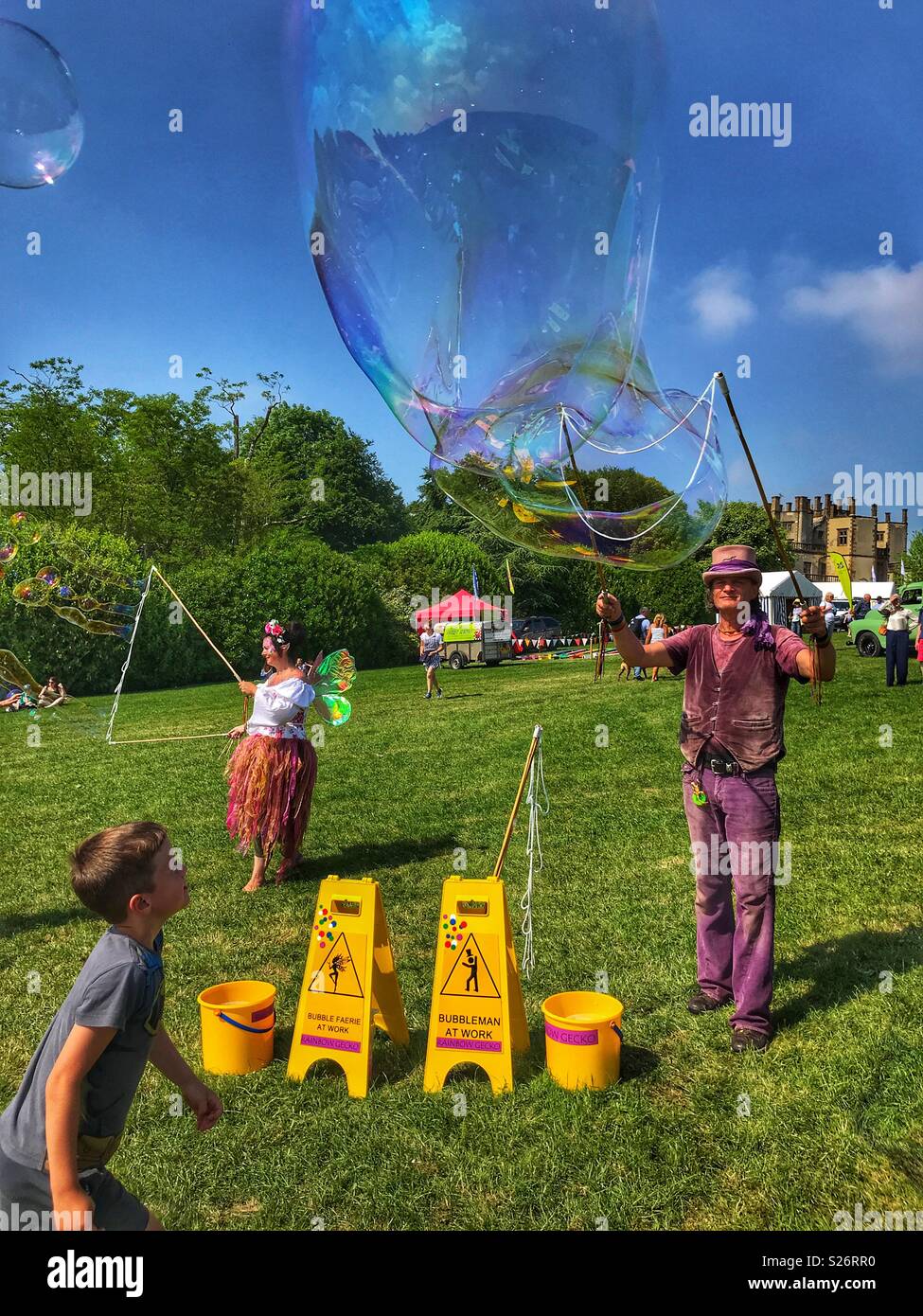 Boy watching man blowing huge soap bubbles, Sherborne Castle Country Fair, Sherborne, Dorset, England - Smartphone Captured Stock Image