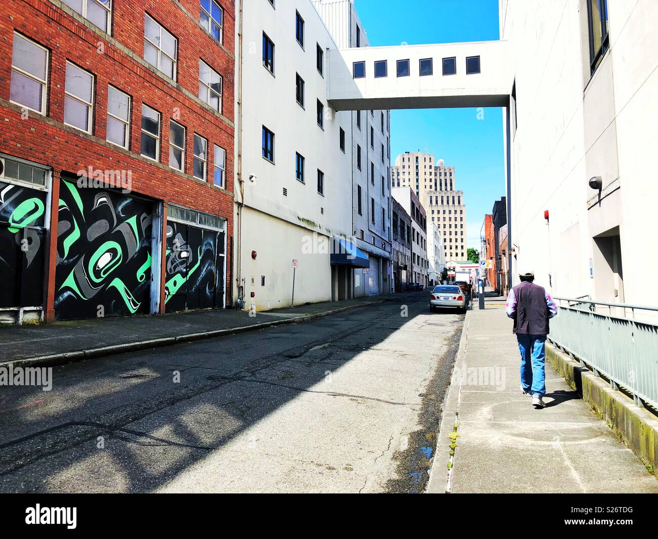 Large mural in style of Pacific Coast Native People and man walking down the back alley in Tacoma WA - Smartphone Captured Stock Image